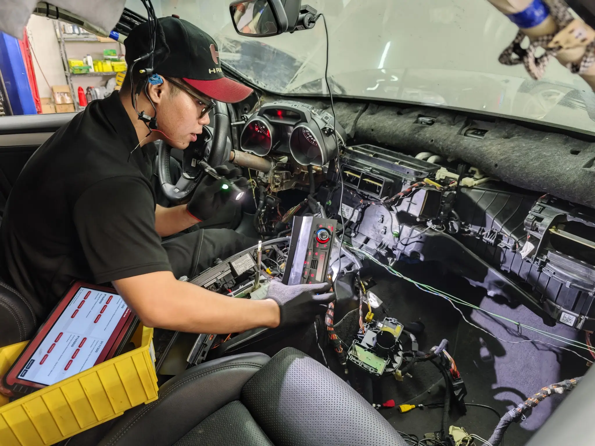 Tú Nguyễn — kỹ sư điện & chẩn đoán BMAP Workshop đang dò hệ thống điện sau taplo một chiếc xe Đức